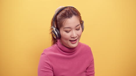 asian woman using a digital tablet and streaming application for happy listening to music on headphones while with playing the dog for relaxed on bright yellow background