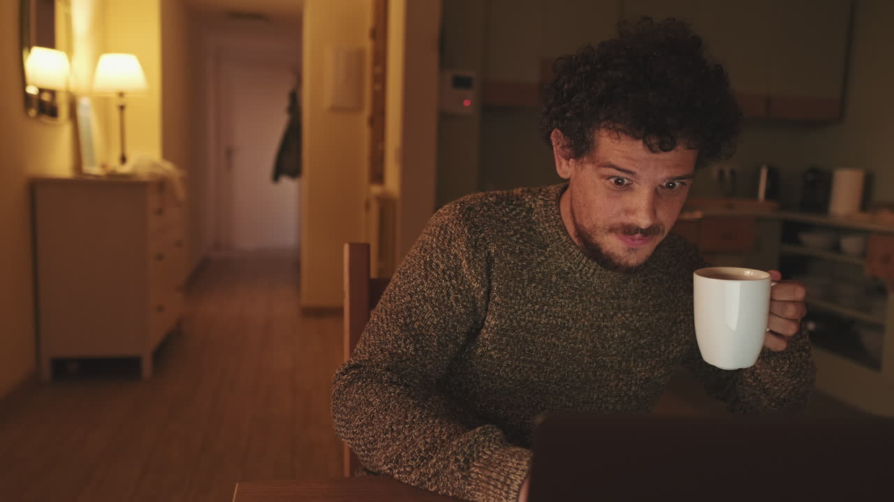 Man drinking coffee while using laptop at home