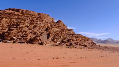 arabian bedouin tents nestled against rugged, red sandstone mountains in desert of wadi rum in jordan, middle east