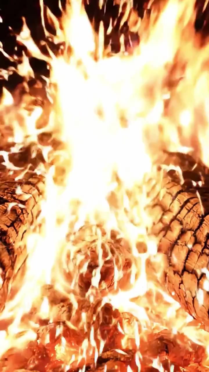 Fiamme Affascinanti Danzano Tra i Ceppi: Una Vista Ravvicinata di un Fuoco Ardente che Illumina le Texture e il Calore del Legno che Brucia
