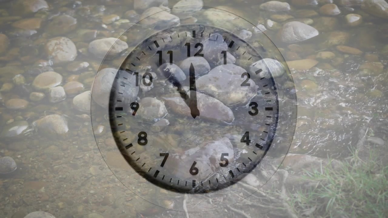 On start transparent clock face fading over stream, clock hands rotating clockwise tracking time