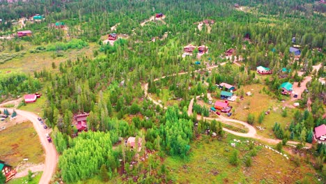 drone aéreo vuela sobre cabañas aisladas en el medio de la nada rodeado de bosque de pinos en un vecindario rural escondido con caminos de tierra