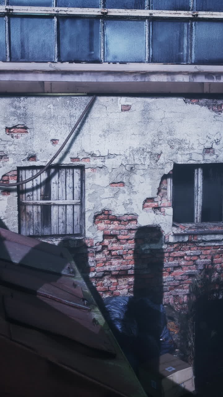 Um edifício industrial abandonado com uma parede de tijolos e uma porta enferrujada.