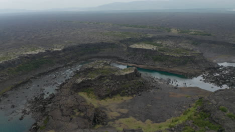 Birds-eye-surreal-panorama-of-black-rock-basalt-cliffs-in-Iceland.-Drone-view-of-Aldeyjarfoss-waterfall-highlands-with-river-flowing-and-volcanic-formations