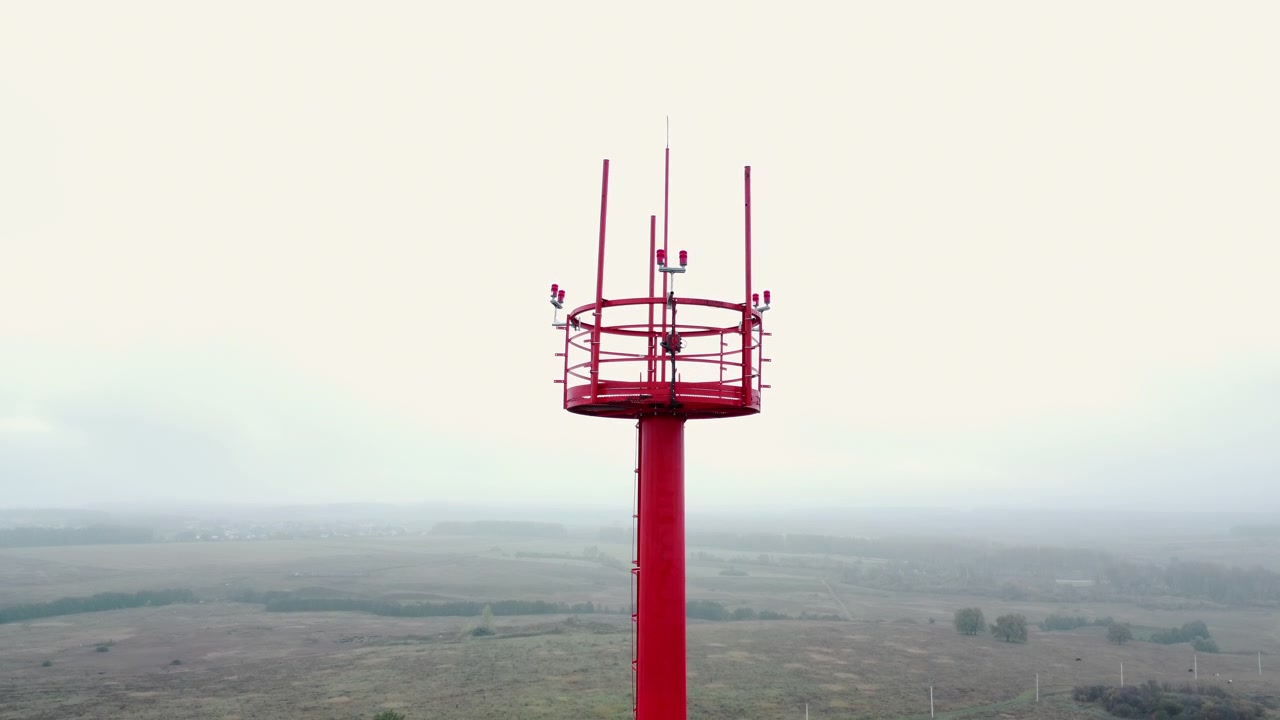 Vista aerea di una torre di comunicazione rossa e bianca in un paesaggio nebbioso