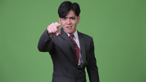 young angry asian businessman pointing to camera