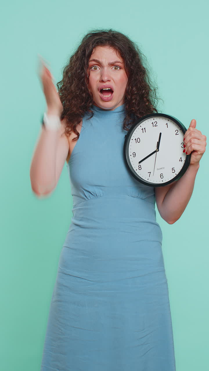 Young woman with anxiety checking time on clock running late to work being in delay deadline