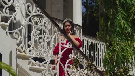 Embracing-the-mystique-of-a-Caribbean-castle,-a-young-woman-dons-a-striking-red-gown-within-its-ancient-walls