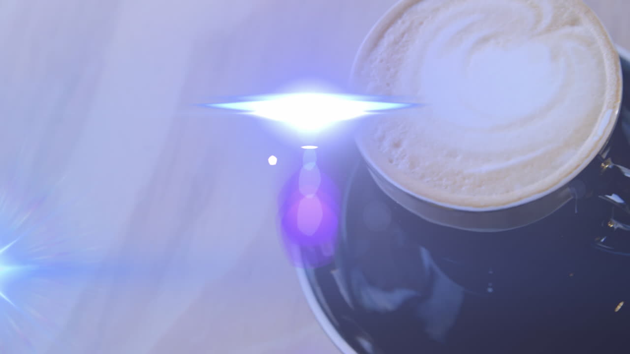 animación de llamaradas de lente moviéndose sobre vista de ángulo alto de la taza de café en la mesa.