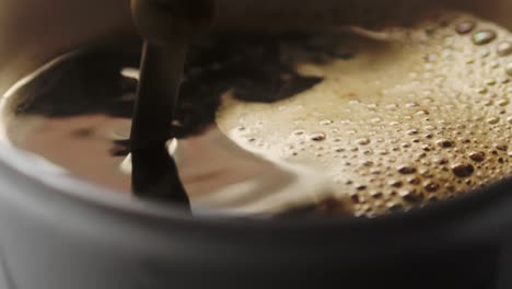 Slow-motion-shot-of-a-spoon-stirring-hot-coffee-in-a-white-mug