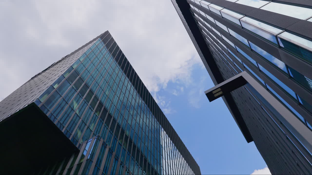 Exteriors of modern skyscrapers and cloudy sky, ground view pan