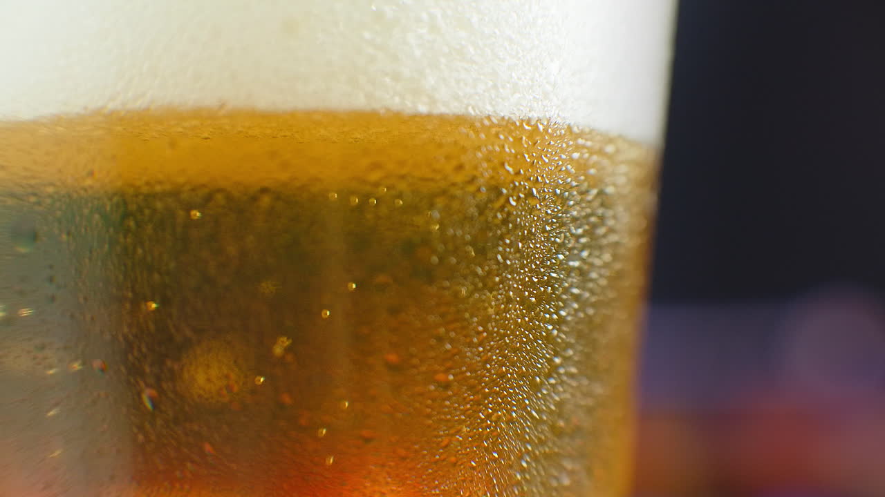 close-up cámara lenta: cerveza fría en un vaso grandes gotas y burbujas en la cerveza