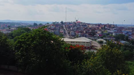 jib down of the beautiful skyline of the city of ibadan, nigeria. the camera slowly moves behind lush, green trees on a sunny summer day