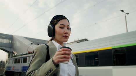 businesswoman at train station with coffee and phone