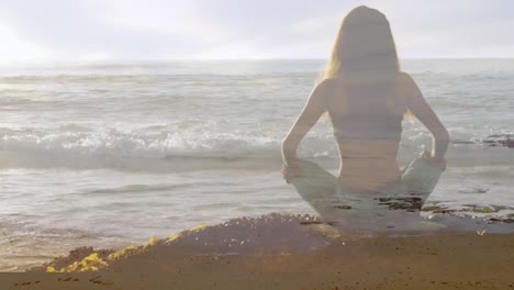 mujer meditando en la playa