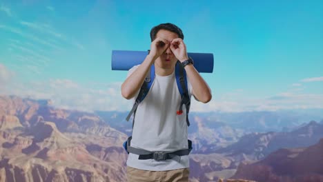 asian male hiker with mountaineering backpack making binoculars gesture looking at something then saying wow while traveling at the top of mountain