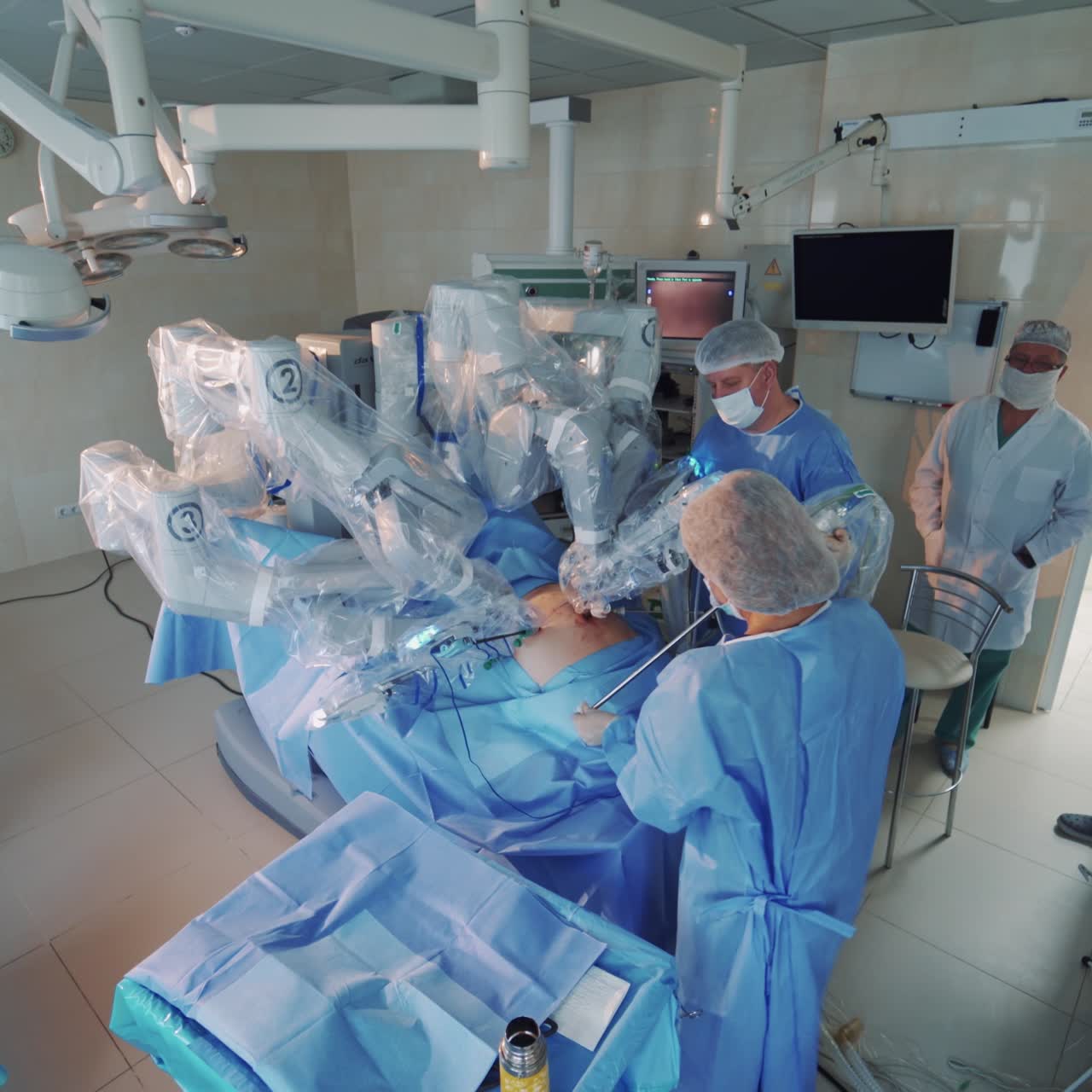 Operating room with modern robotic device. Medical surgical robot doing surgery. Group of surgeons control the work of da Vinci system. Modern medical equipment.