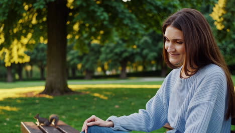 woman sitting in a park with a squirrel