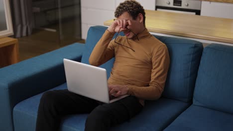 diverse ethnic young man using laptop on the sofa and got tired