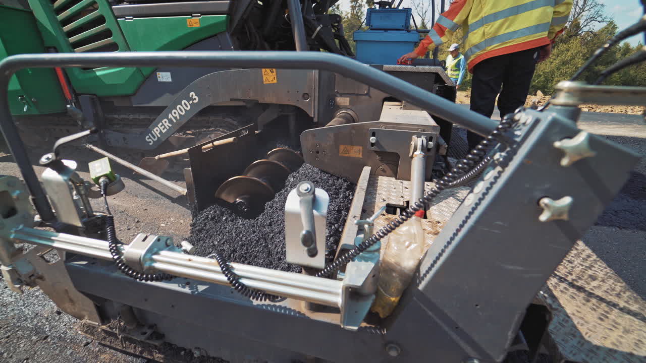 Road repairing works. Operating of asphalt paver machine during road construction and repairing works