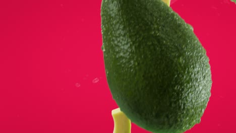aguacate con rebanadas y salpicaduras que caen sobre el fondo de fucsia