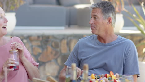 senior man enjoying in garden lunch with diverse senior friends, talking and relaxing together