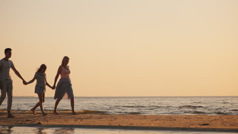 Family-With-A-Child-Goes-To-The-Sea-At-Sunset