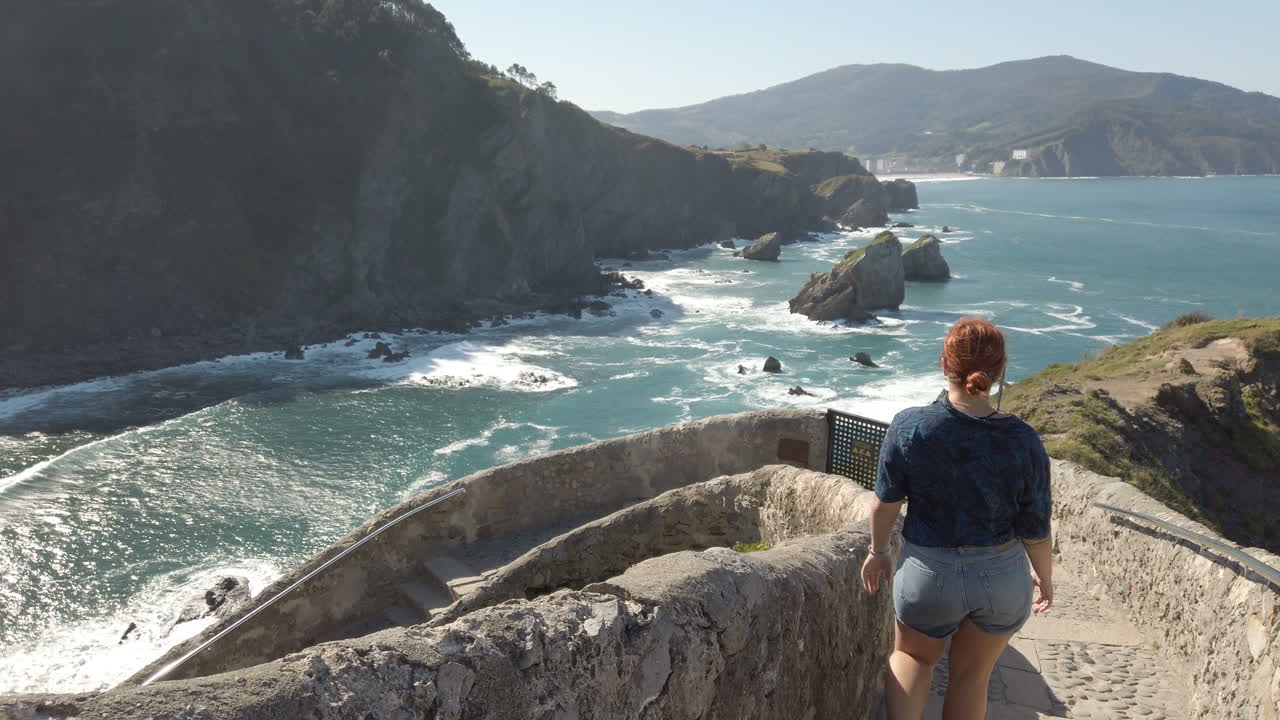 Woman overlooking the ocean from a cliffside path