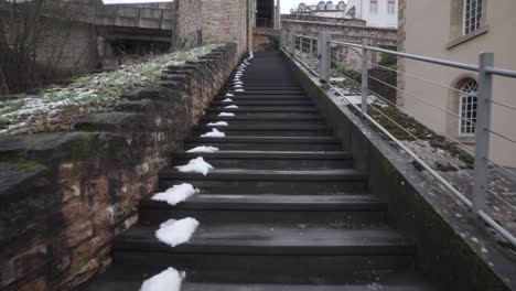 Slowly-ascending-an-outdoors-stone-staircase,-snow-melting-in-the-shadows