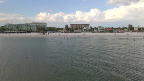 Aerial-view-of-people-walking-at-the-beach-and-waterfront-houses-in-Fort-Myers-beach,-Florida