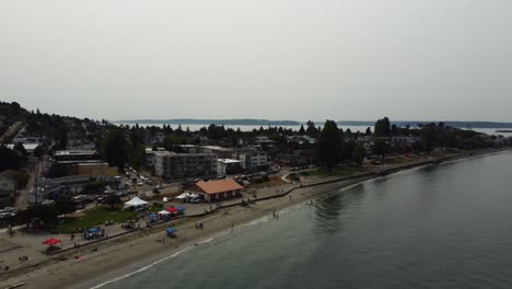 Clockwise-drone-shot-showcasing-people-relaxing-at-Alki-Beach-in-the-Seattle-suburbs