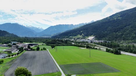 Lush-green-fields-and-mountains-in-rothenbrunnen,-switzerland-on-a-sunny-day,-aerial-view