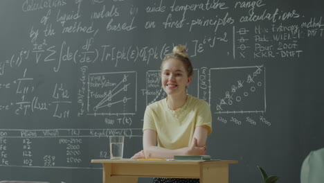 young woman presenting in front of a blackboard with equations