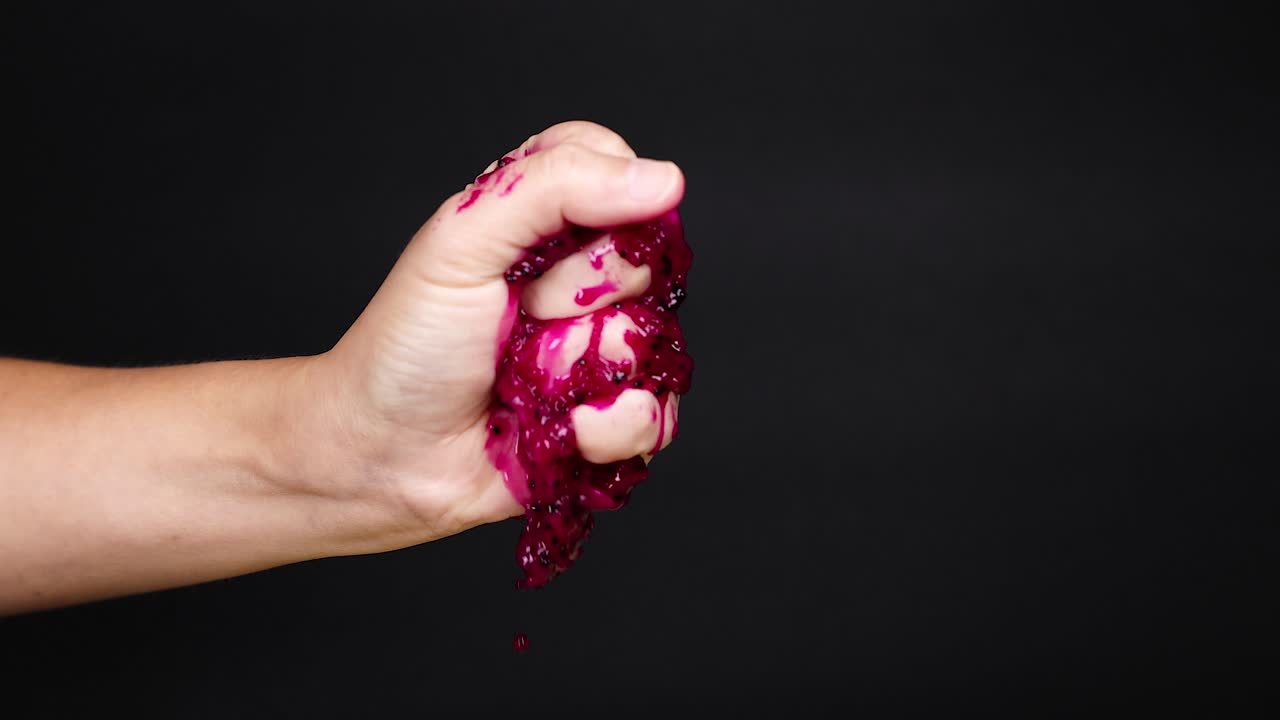 la mano exprimiendo la fruta del dragón, el jugo goteando