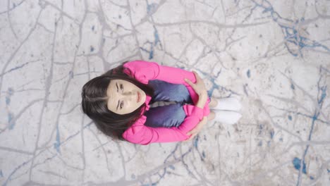 Top-view-of-sad-lonely-young-woman-sitting-on-floor-at-home-stressed-and-tired.