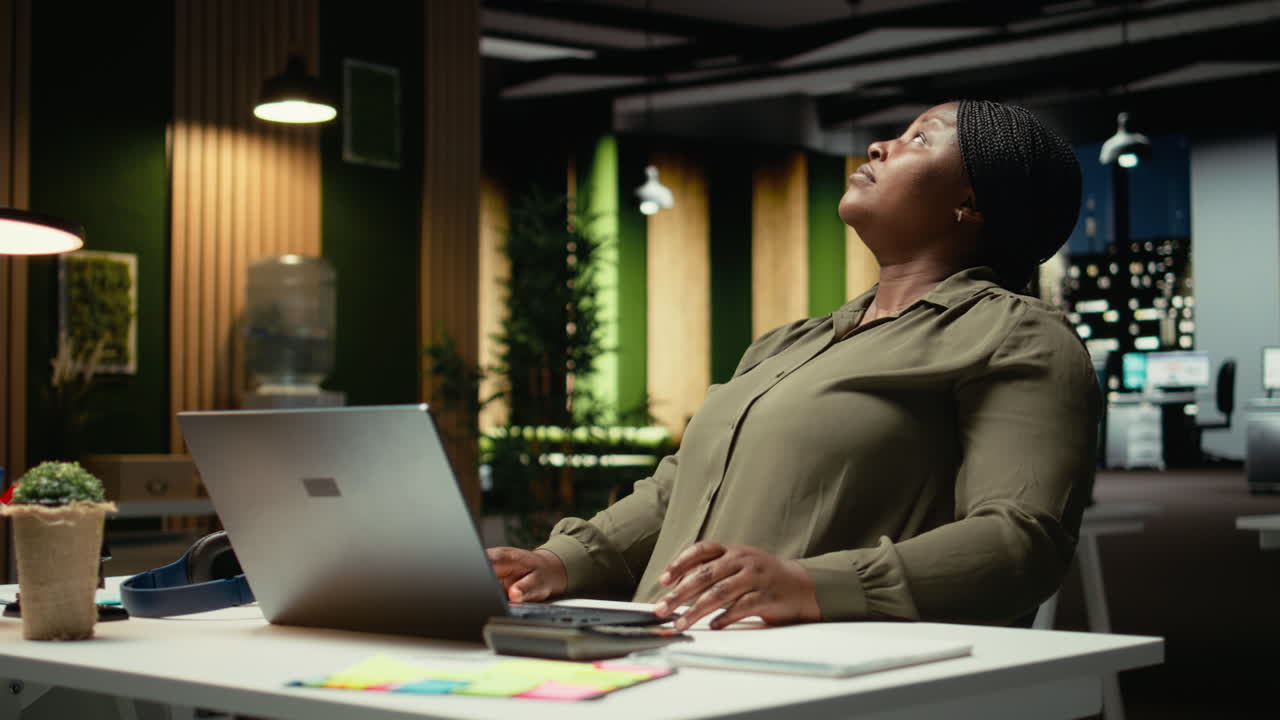 Black consultant focusing on a complex problem in a dark office at midnight