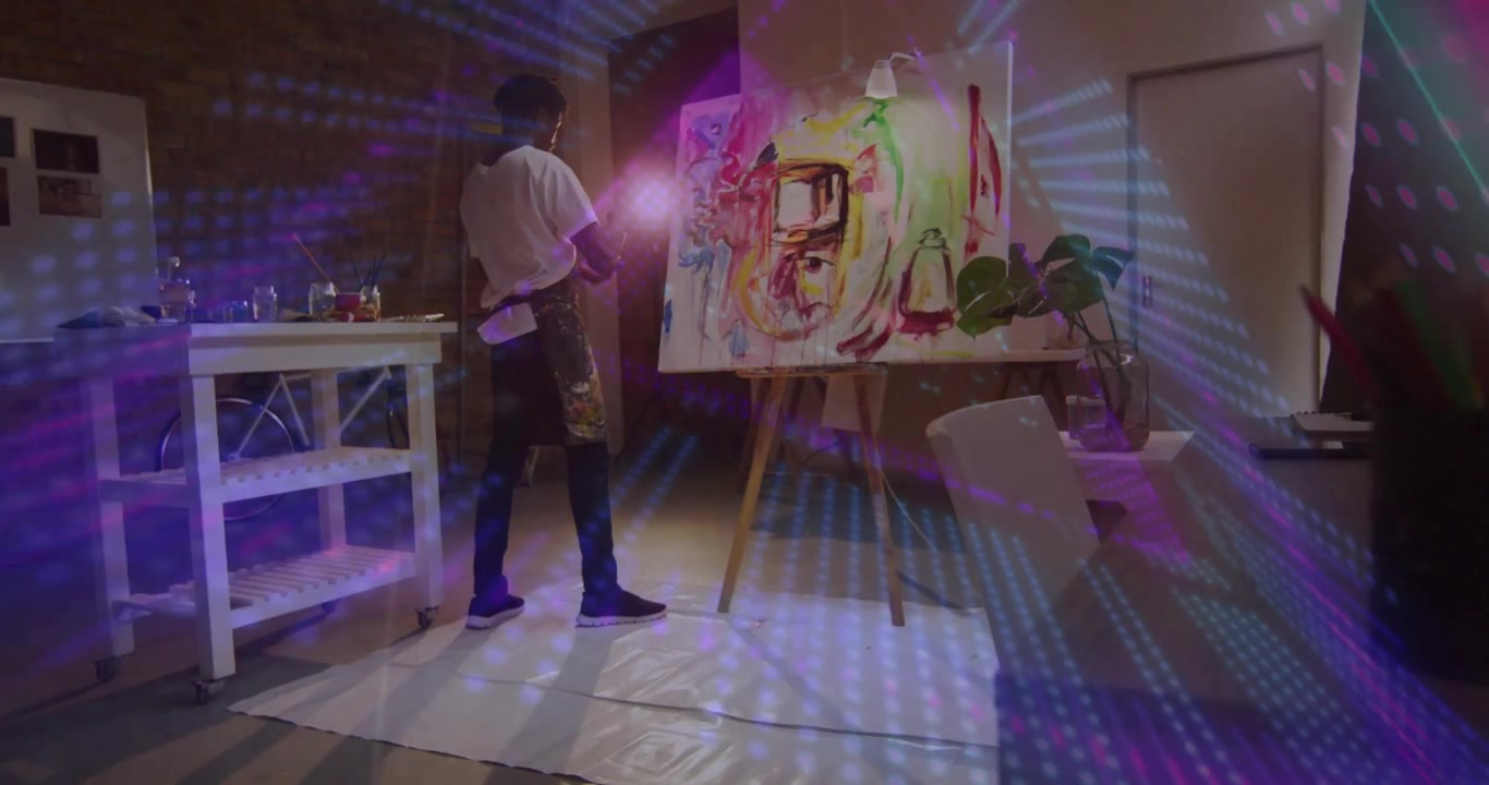 Artista che solleva il pennello e tiene una lampada, dipingendo tratti per affinare la composizione sotto una luce a motivi.