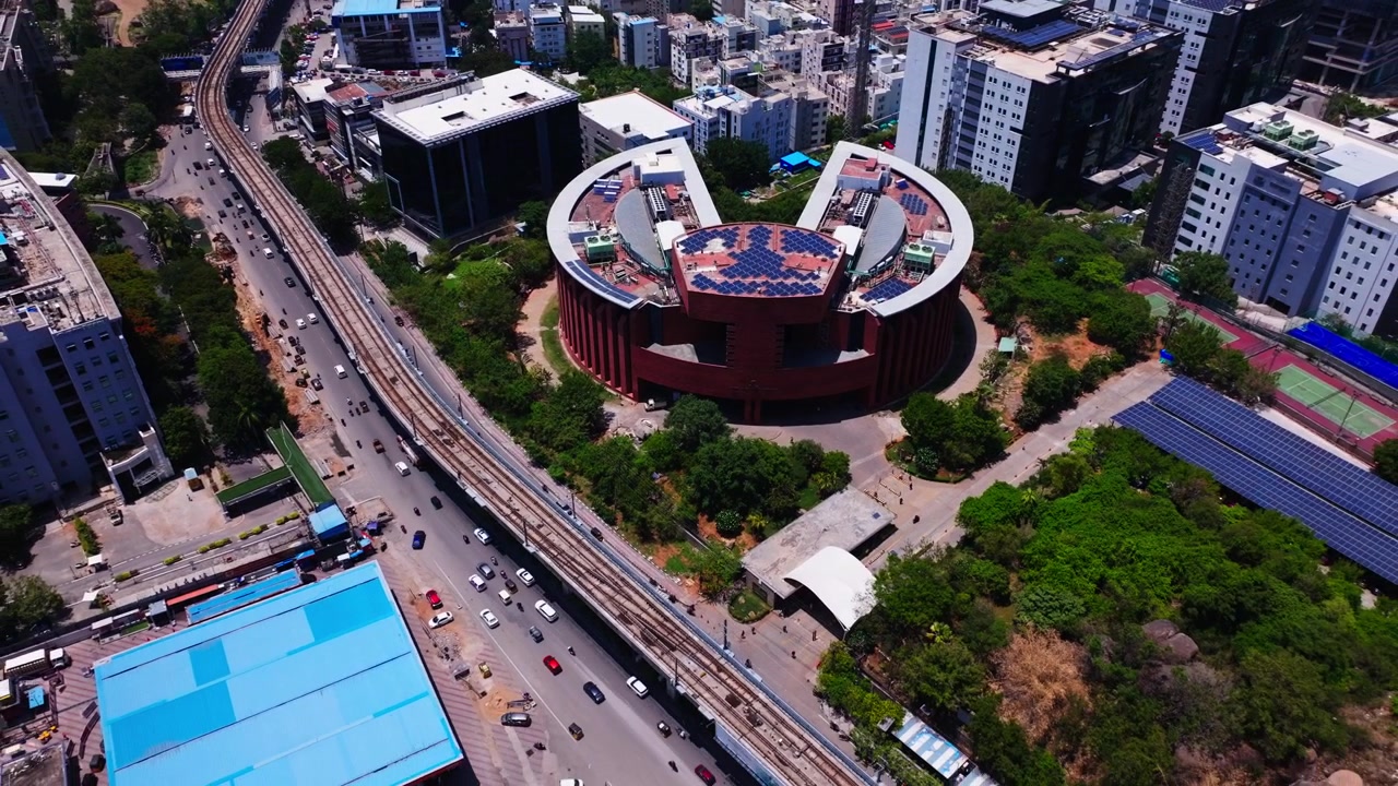 Parque TCS Deccan con paneles solares, línea de metro y flujo de tráfico en Hitec City, Madhapur, Hyderabad, Telangana, India. De día, toma en retroceso, toma de dron, 4K