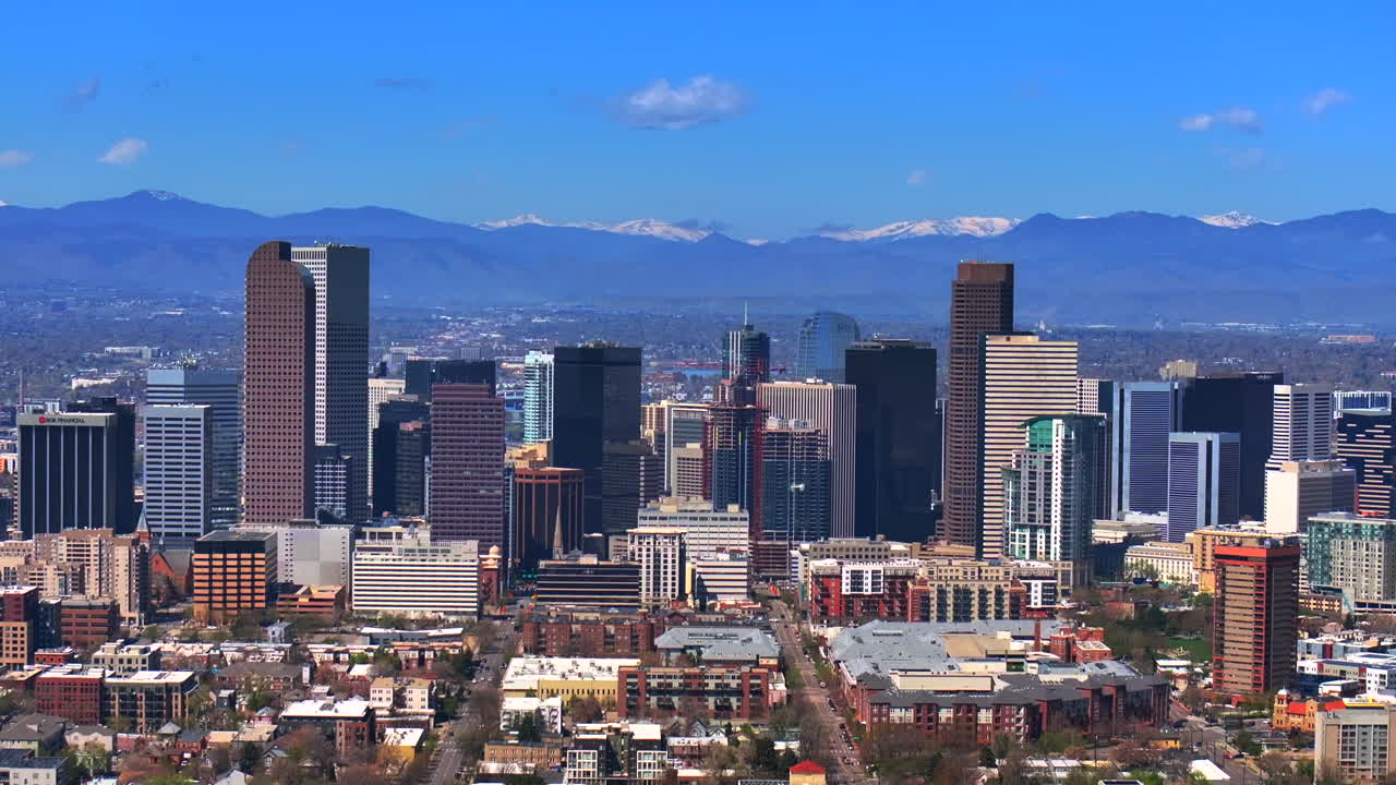 Downtown Denver Colorado City Park vibrant spring summer aerial drone sunny blue sky snow capped Rocky Mountains front range cityscape green lush grass trees blossom forward motion