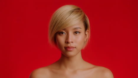 portrait of an asian woman with blonde short hair on red background