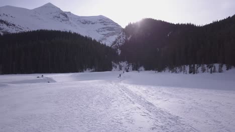 探险滑雪者在岩石山脚下穿过半冻结的河流