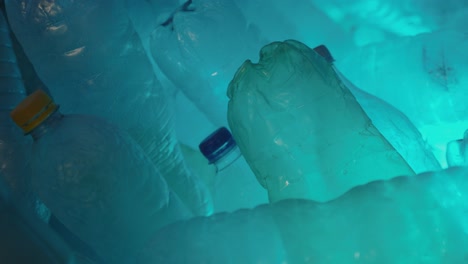 Detail-shot-of-empty-water-bottles-illuminated-with-a-blue-and-green-light-changing-color