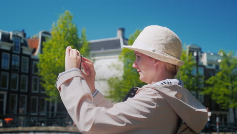 a middle-aged woman takes pictures of amsterdam