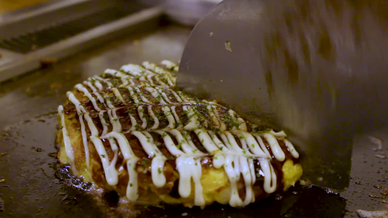 comida japonesa okonomiyaki cocinada y cortada por la mitad por un experto