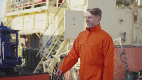 trabajador del puerto en uniforme naranja está caminando en el sitio del puerto de carga. cámara lenta