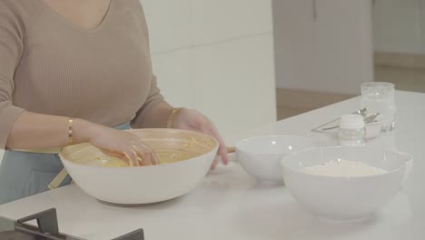 a chef's hand pouring granulated sugar over bread dough in a baking dish