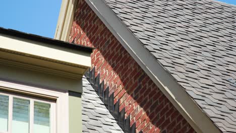 Explore-the-architectural-finesse-of-a-brick-home's-roof,-highlighting-the-eave-and-gable,-as-well-as-the-seamless-seam-between-the-roof-and-the-wall-in-this-detailed-stock-video