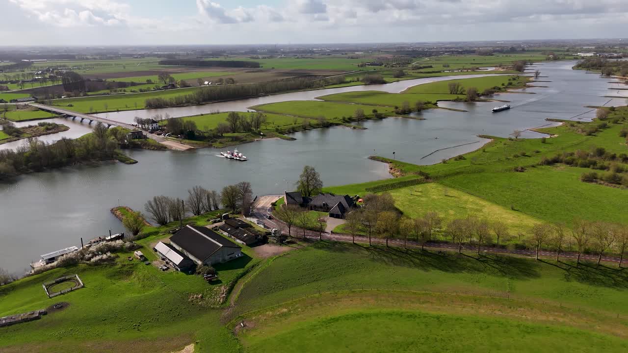 Vista Aérea de un Ferry Cruzando un Río Ancho en un Paisaje Rural Verde.