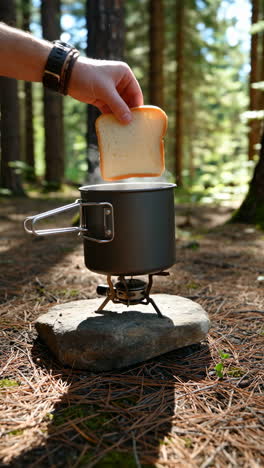 outdoor cooking: toasting bread on a portable camp stove in the forest