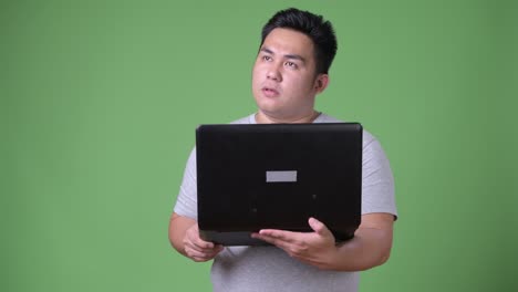 초록색 배경에 젊은 잘생긴 과체중 아시아인